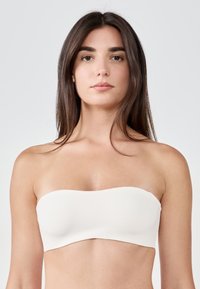 Strapless bandeau bra in solid white fabric, smooth texture, seamless design, with a curved top edge and no visible hardware or embellishments.