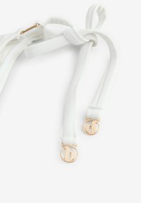 Suspendere elastice albe cu clipuri metalice de culoare aurie, prezentând un design cu nod în centrul lor și o textura netedă, moale.