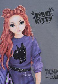 Felpa viola con una grafica di un gatto nero, circondata da stelle e da una luna crescente. Presenta una cintura con borchie e il nome "Lexy."