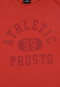 Czerwona bawełniana koszulka T-shirt z dużym, ciemnoczerwonym nadrukiem, na górze napis "ATHLETIC", a na dole "99 PROSTO", okrągły dekolt, krótkie rękawy.