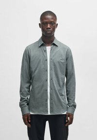 Een button-up shirt in heathered grijs stoffen, met een witte placket, lange mouwen en een ronde zoom. Klein logo op de borst.