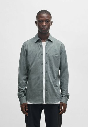 Button-up shirt in heathered gray fabric, featuring a white placket, long sleeves, and a rounded hem. Small logo on the chest.