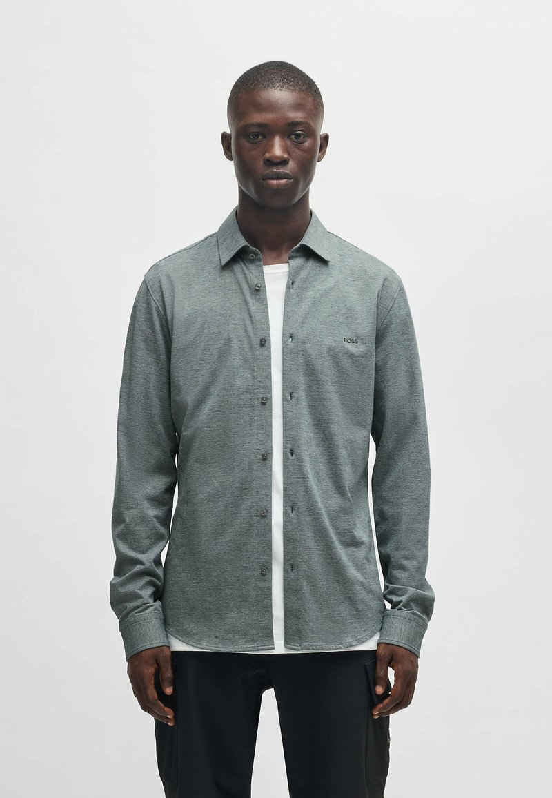 Een button-up shirt in heathered grijs stoffen, met een witte placket, lange mouwen en een ronde zoom. Klein logo op de borst.