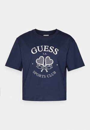 Tengerészkék pamut póló rövid ujjakkal, kerek nyakkal és fehér "GUESS L.A. SPORTS CLUB" grafikával, amely két teniszütőt ábrázol.