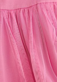 Różowa spódniczka tutu z miękkim, elastycznym pasem i warstwowym, przezroczystym tiulem o strukturalnym, siatkowym wzorze.