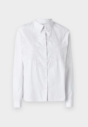 Balta marškinėliai su ilgomis rankovėmis, puošti sudėtingais baltais siuvinėjimais priekyje. Lygus, lengvas audinys.