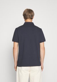 Tmavomodrá polokošeľa s golierom a krátkymi rukávmi. Má jednofarebný dizajn, klasický strih a jemné šitie na golieri.