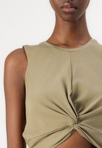 Olive green, sleeveless top made of soft fabric, featuring a twisted knot detail at the center and a rounded neckline.