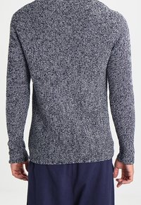 Marineblauer und grauer gestrickter Pullover mit langenÄrmeln und Rundhalsausschnitt. Strukturmuster über den Stoff verteilt, taillierte Silhouette.