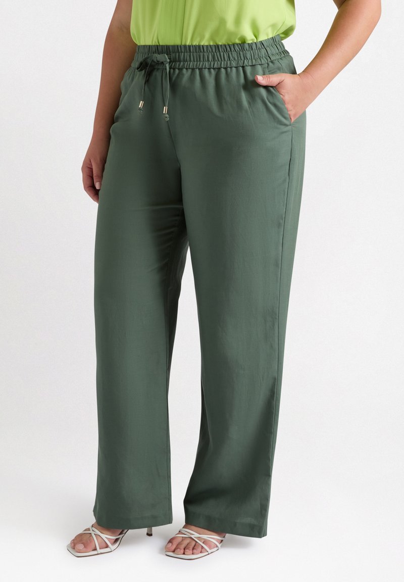 Pantalons larges de couleur vert foncé, en tissu lisse, dotés d'une taille élastique avec cordon de serrage et de poches latérales.
