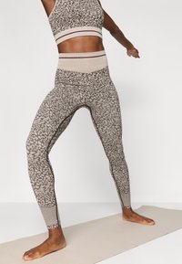 Κολάν ψηλής μέσης και συνδυασμένο cropped τοπ σε στίγματα καφέ χρώματος. Φτιαγμένα από ελαστικό υλικό με αντίθετα ραβδωτά στοιχεία.