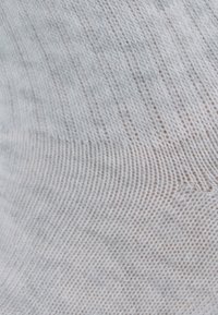 Biała dziana tkanina o delikatnej, gładkiej fakturze. Charakteryzuje się subtelnym wzorem ciasnych i luźnych ściegów, co nadaje jej miękki wygląd.