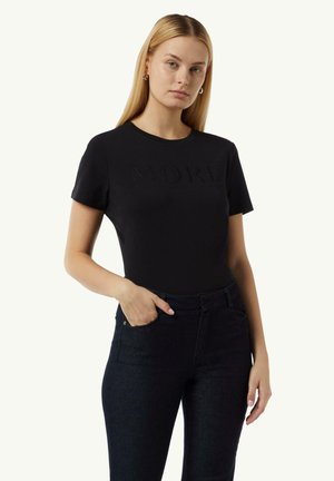 T-shirt noir à manches courtes avec le mot "MORE" en relief sur le devant, complété par un pantalon en denim foncé. Tissu lisse, design ajusté.