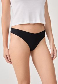 Parte inferior de bikini negra con un diseño frontal en forma de V, hecha de material suave. Presenta una cobertura mínima y costuras laterales que se integran a la perfección.
