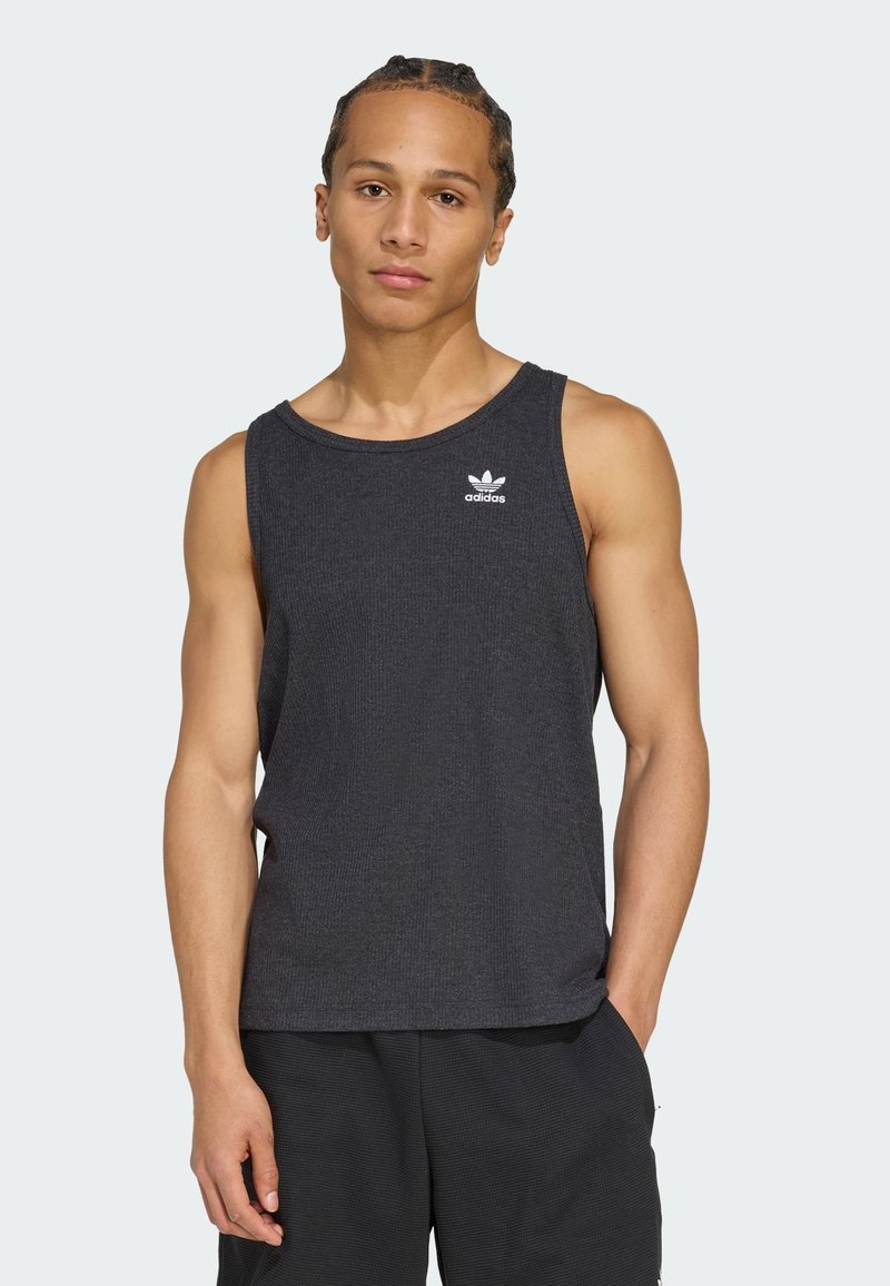 Tricou fără mâneci, de culoare gri închis, cu textură răsucită. Prezintă un logo alb Adidas în zona stângă a pieptului. Design simplu, fără ornamente.