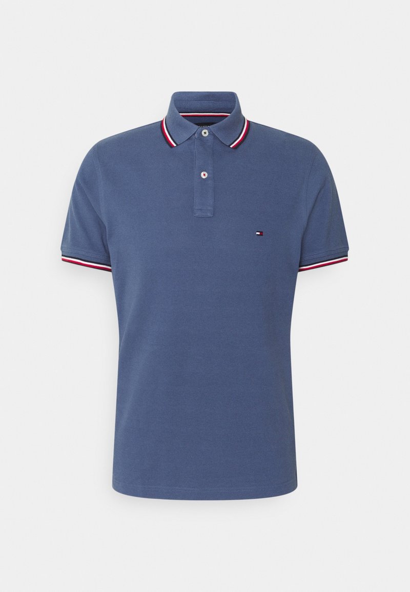 Polo bleu à manches courtes avec liseré blanc, rouge et bleu marine sur le col et les manches, et un petit logo sur la poitrine gauche.