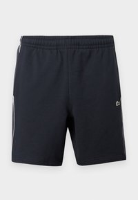 Shorts de sport noirs avec une taille élastique, des bandes blanches sur les côtés et un petit logo de crocodile vert sur la jambe droite.