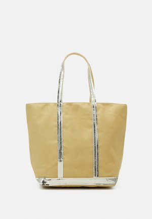 Beige tote bag with two long handles decorated with vertical and bottom silver sequin stripes on a white background.
