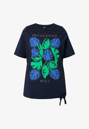 Marineblå kortærmet skjorte med grønne og blå tropiske bladmotiver og teksten "Find din indre fred," med en lille knude i sømmen.