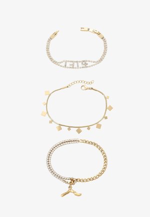 Tre braccialetti: superiore con strass trasparenti e componenti in oro, centrale con forme geometriche e una catena, inferiore con catena dorata e un ciondolo.