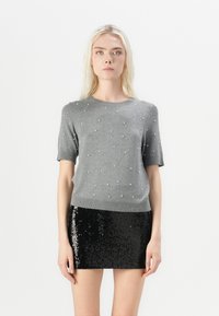 Gray knitted short-sleeve sweater with pearl embellishments; paired with a black sequined mini skirt. Smooth texture with a fitted design.