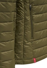 Gilet rembourré vert olive avec texture matelassée horizontale, une poche zippée sur le côté, et une étiquette rouge présentant le logo de la marque à l'ourlet.