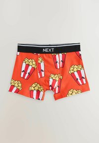 Červené boxerky so vzorom popcornu. Čierny pás so štítkom „NEXT“. Mäkký materiál, priliehavý strih a hravý grafický dizajn.