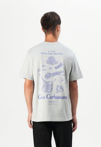 Helles graues T-Shirt mit blauen Lin Zeichnungen von Lebensmitteln und Text auf der Rückseite, kurzen Ärmeln und einem entspannten Schnitt.