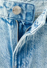 Svetlomodrá rifľová tkanina s viditeľným zipsom a kovovým cvokom. Vyznačuje sa textúrovaným vzorom tkania a kontrastným šitím.