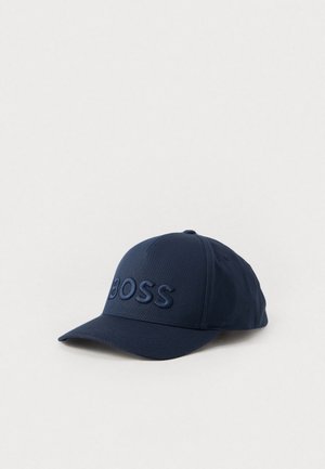 Navyblå baseballkasket med buet skygge og hævet broderet BOSS-logo på frontpanelet mod ensfarvet baggrund.