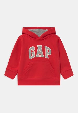 Czerwona bawełniana bluza z kapturem, z przednią kieszenią kangurka i szarą aplikacją z napisem "GAP". Miękka w dotyku, z prążkowanymi mankietami i ściągaczem u dołu.