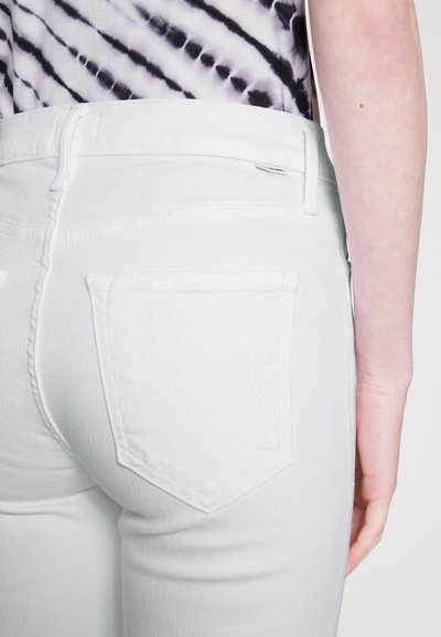 Hvite denimjeans med en tettsittende design, som viser en baklomme med et subtilt brodert mønster og en jevn tekstur.