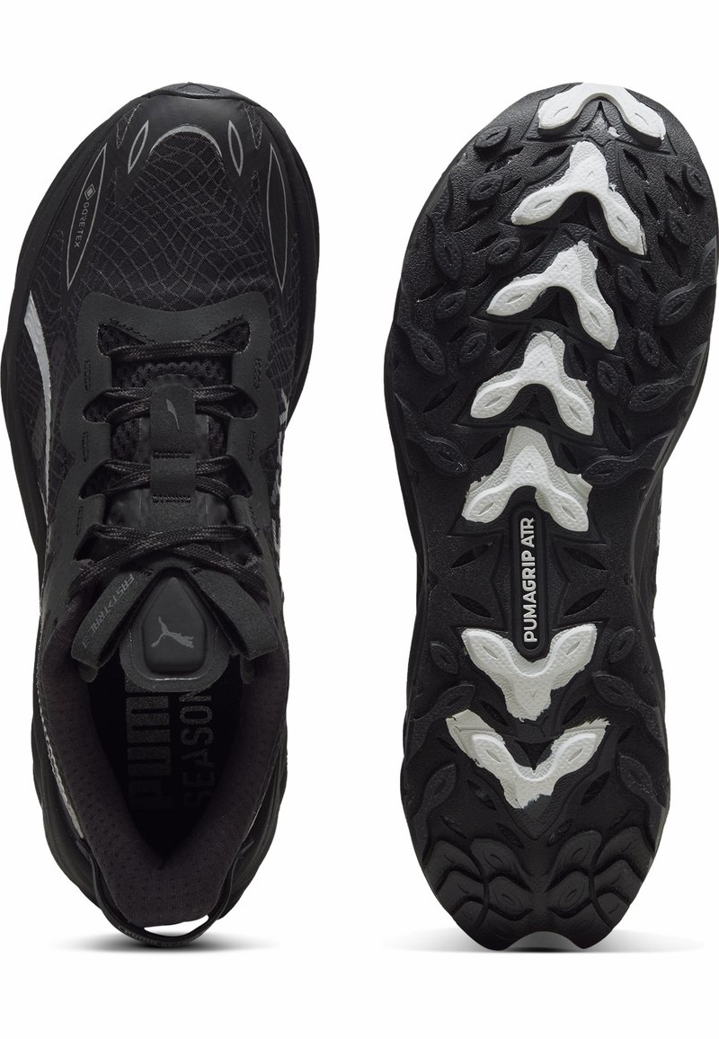 Baskets de sport noires avec tige synthétique texturée, fermeture à lacets et semelle en caoutchouc avec accents blancs et motif de grip multidirectionnel.