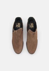 Hnědé semišové slip-on boty s hladkým svrškem, kulatou špičkou a minimalistickým designem. Interiér má texturovanou stélku s logem.