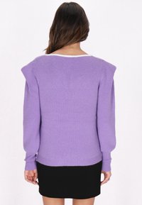 Lila Strickpullover mit Schulterakzenten, langen Ärmeln und gerippter Struktur. Weißer Ausschnittsausschnitt und eine etwas lockere Passform.