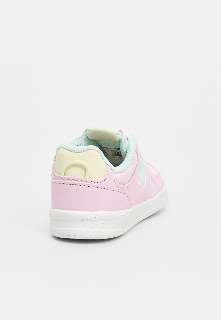 Baskets synthétiques roses avec une semelle blanche, rehaussées d'un col vert menthe et d'un logo. Texture lisse, design bas.