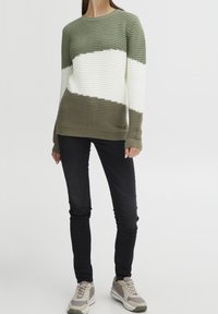 Randig tröja i grön och vit ribbad stickning, med långa ärmar och rundad halsringning. Matchas med svarta slim-fit jeans och sneakers.