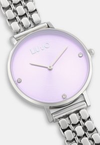 Orologio argento con cassa rotonda, quadrante a gradiente lavanda, tre dettagli in cristallo e bracciale in metallo lucido con maglie ovali.