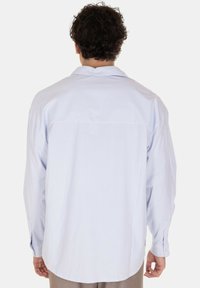 Camicia a maniche lunghe a righe blu chiaro con colletto regolare, polsini con bottone e orlo dritto. Tessuto morbido con una texture liscia.