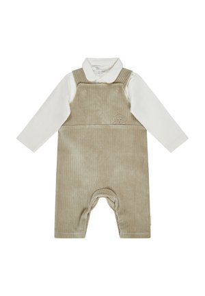 Beige Corduroy-Latzhose mit einem weißen Langarmshirt darunter. Besitzt ein kleines gesticktes Hundedesign auf der Vorderseite und Knopfdetails.