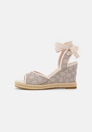 Beige kile-sandal med ankelbindebånd, mønstret stof øverste, flettet espadrille-ydersål og åben tå.