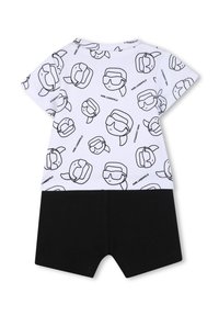 Top alb cu mâneci scurte, imprimeu negru cu desene animate și pantaloni scurți negri. Material din bumbac, croială lejeră, design grafic cu motive de capete.