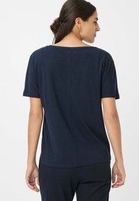 Marineblå kortærmet t-shirt med lige snit og subtil detalje i bagsømmen, lavet af blødt, letvægtsstof.