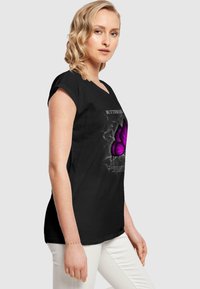 Black t-shirt with short sleeves featuring a purple butterfly graphic and white text design. Soft fabric, relaxed fit, and casual style.