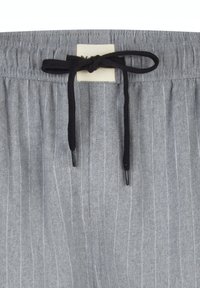 Grijze stof met een fijne streep in zwart, met een zwarte koordstrik in een strikje aan een elastische tailleband, voorzien van een klein wit label achter de strik.