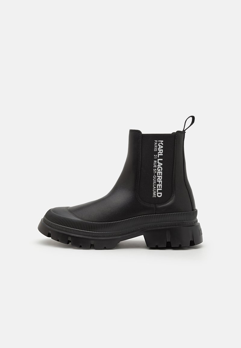 Botines negros de tobillo hechos de goma suave con una suela gruesa, paneles laterales elásticos y detalles del logo en blanco en el tubo.