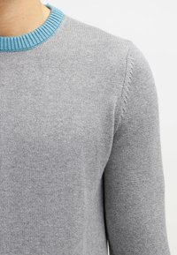 Grau gestrickter Pullover mit strukturiertem Finish und runder Ausschnitt, der über einen kontrastierenden hellblauen Rippenbesatz verfügt.