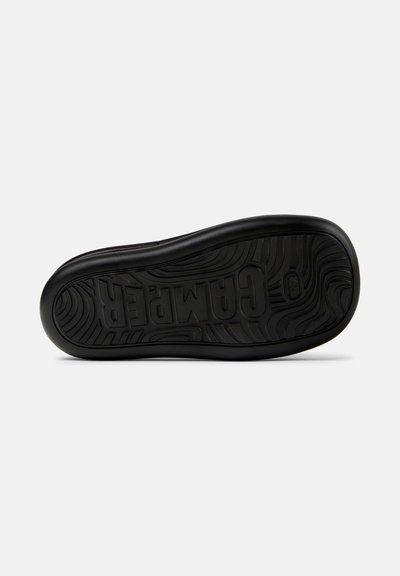 Sort gummisko sål med en bølget tekstur og det præget "Campers" logo. Designet inkluderer buede linjer og riller for optimal greb.