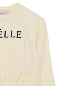 Maglione crema con trama a coste, caratterizzato da un collo rotondo e lettere nere. Include fessure laterali per un ulteriore dettaglio di design.