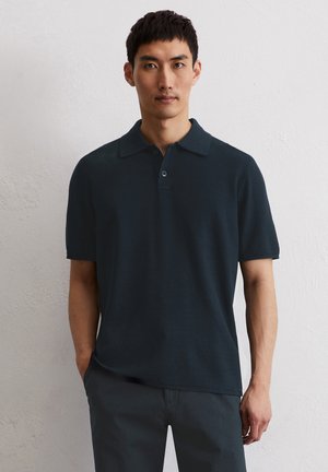 Dunkelblaues Polohemd mit strukturiertem Finish, kurzen Ärmeln und klassischem Kragen. Verfügt über eine Knopfleiste mit drei Knöpfen und seitlichen Schlitzen am Saum.